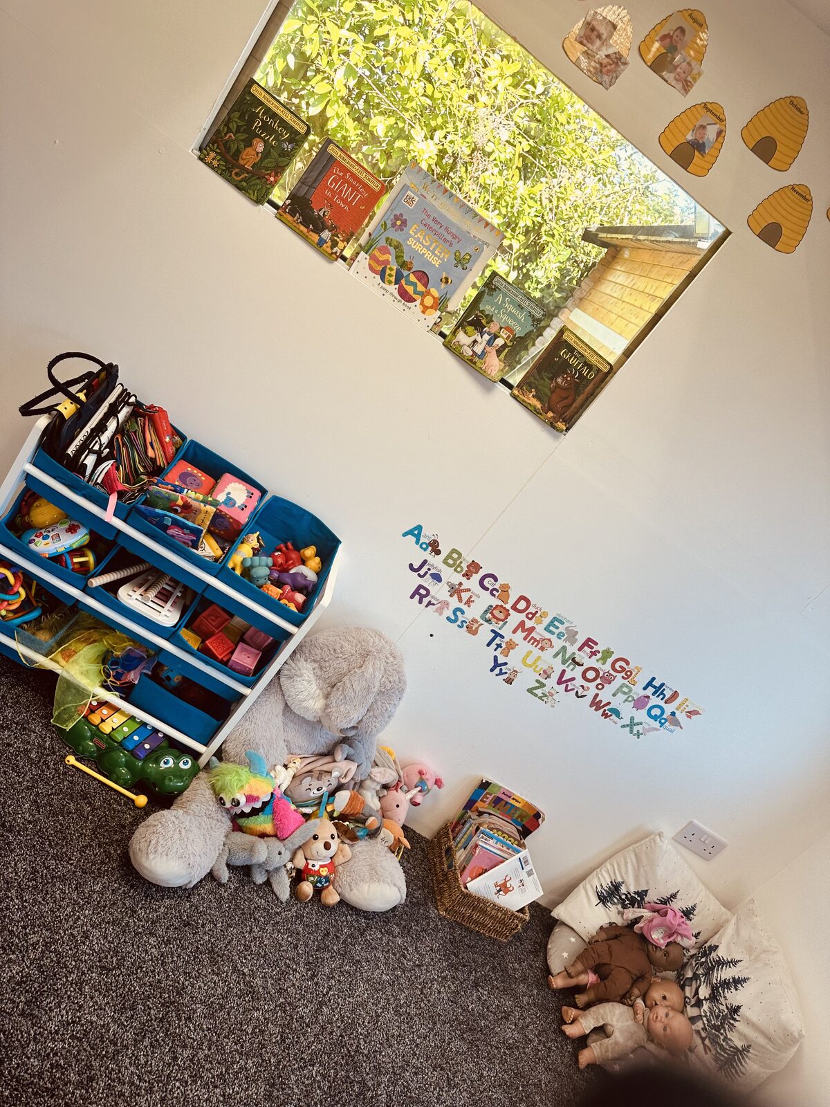 Book display, toy storage and soft toys in the cabin play area at Stewart Street nursery, Crewe