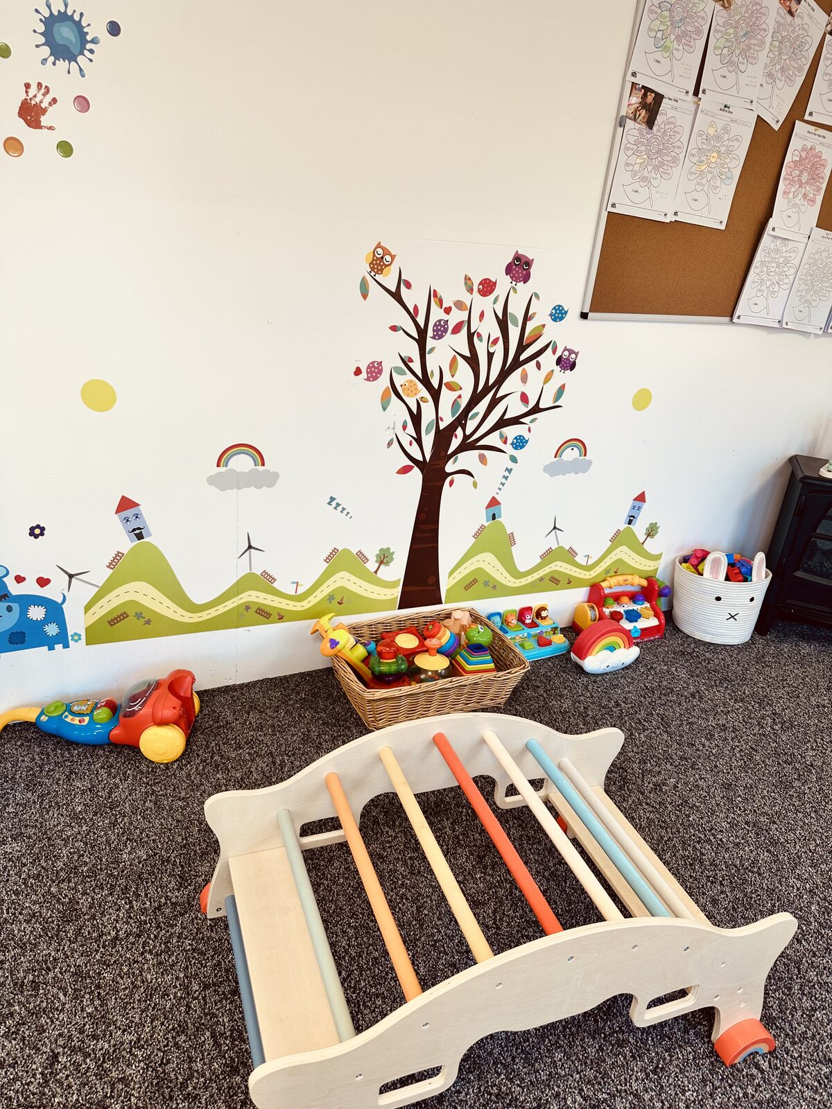 Baby room with low wooden climbing frame at Stewart Street nursery, Crewe